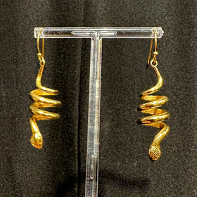 brass spiral cobra earrings on stand - shop in background